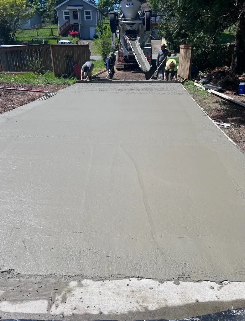 A group of people are working on a concrete driveway.