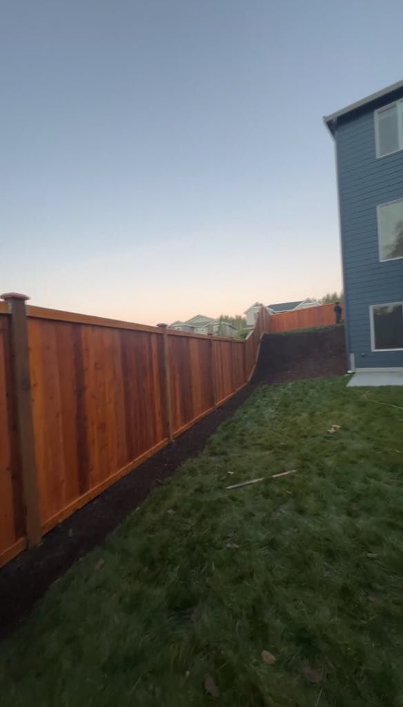 A wooden fence is in the backyard of a house.