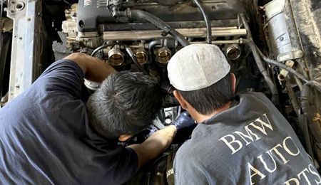 A person in a protective suit is working on a car door.