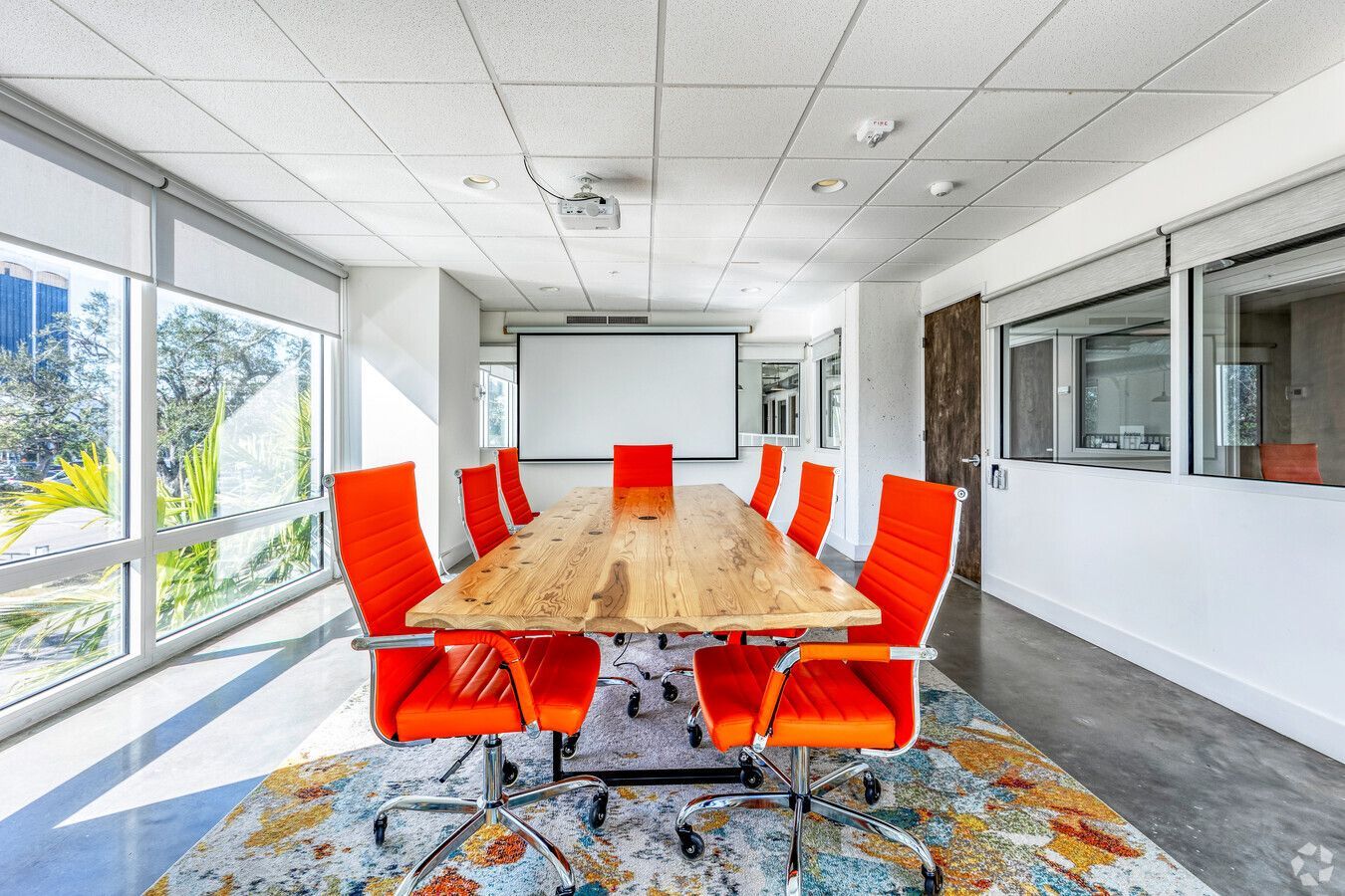 A conference room with a long wooden table and orange chairs.
