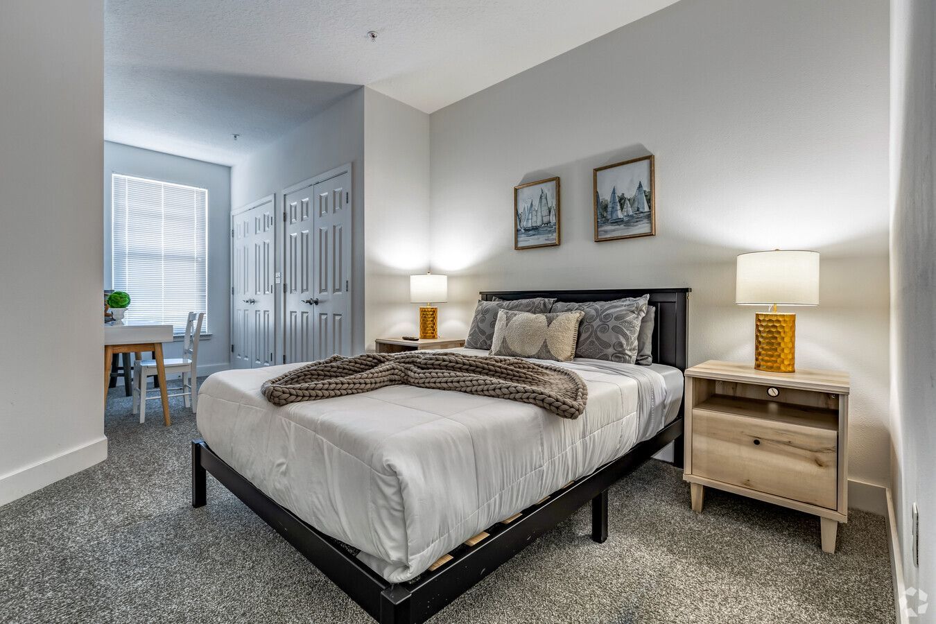 A bedroom with a bed , nightstand , lamps and a window.