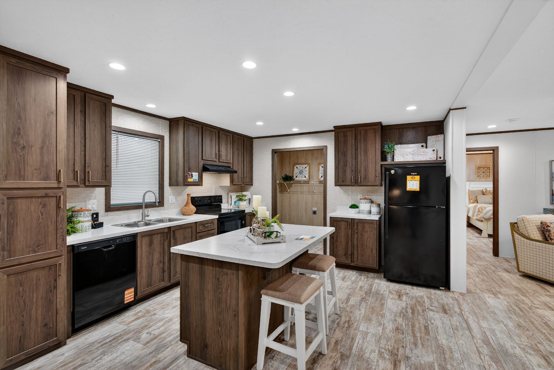 Modern kitchen with wood cabinets, island seating, black appliances, and light wood flooring