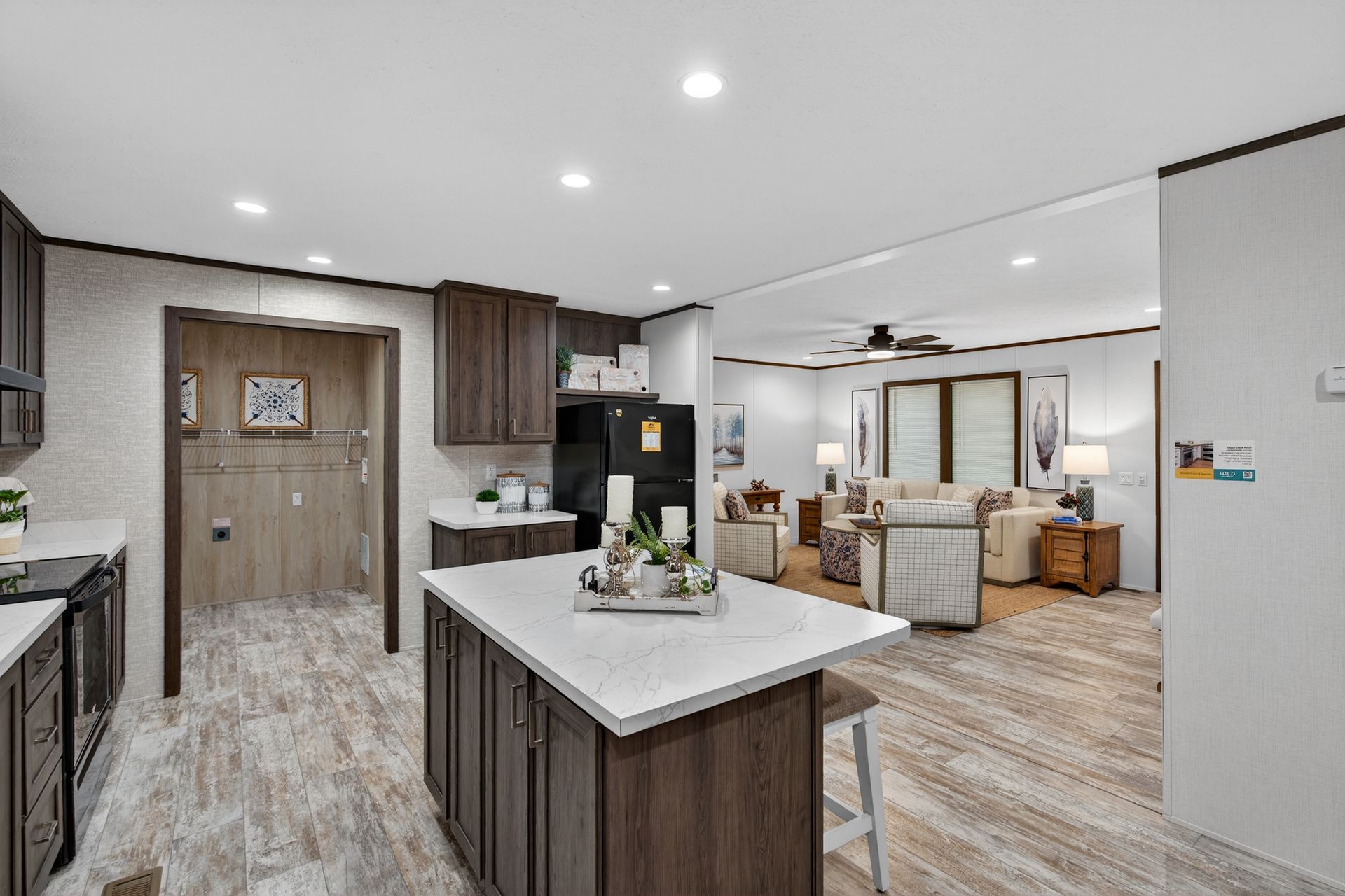 Bright open kitchen and living area with wood cabinets, white island, and light wood flooring.