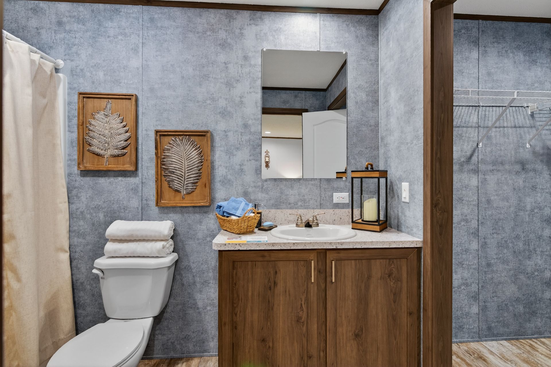Modern bathroom with wood vanity, white toilet, gray walls, and decorative framed wall art.