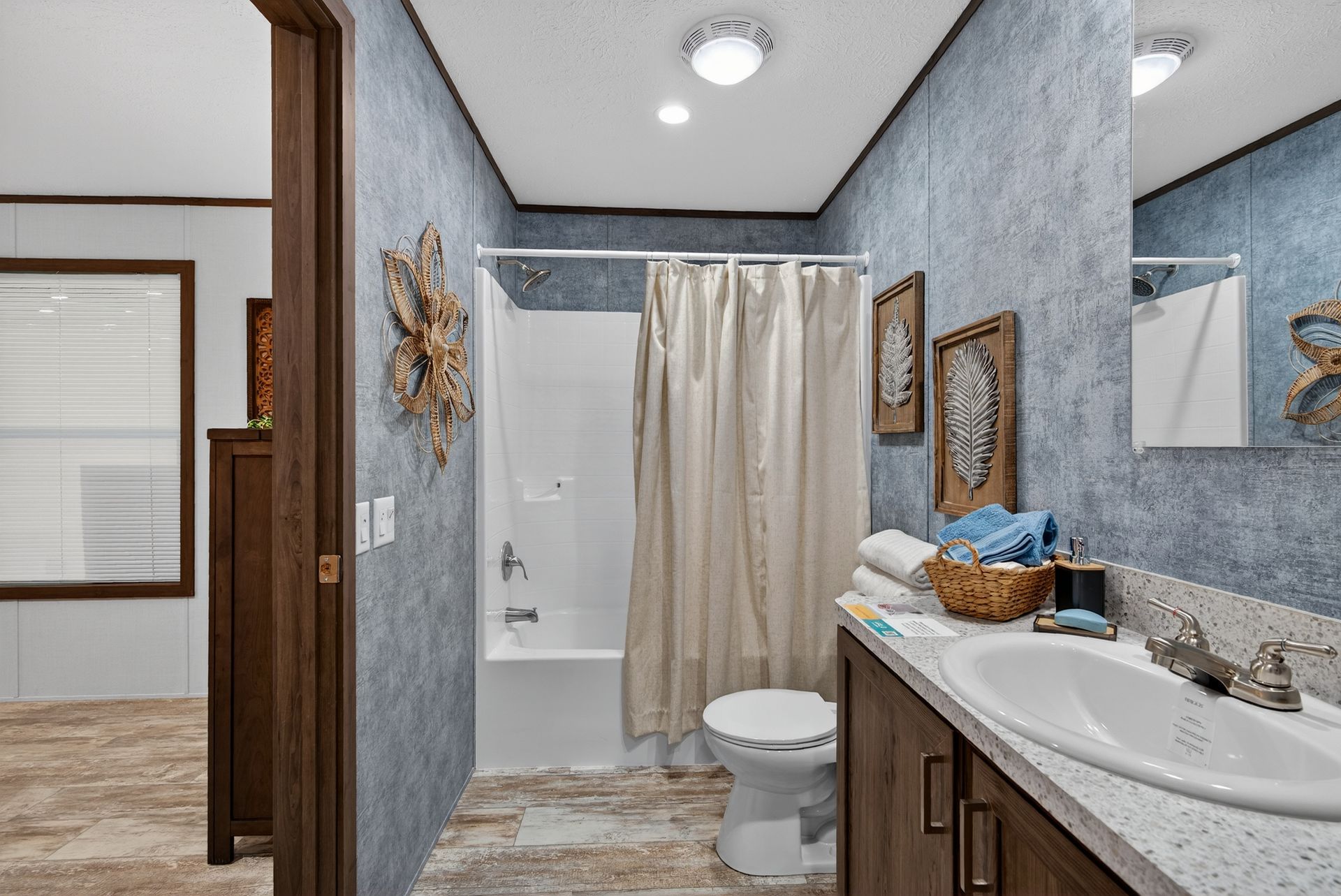 Small bathroom with white tub-shower, toilet, and dark wood vanity with granite countertop.