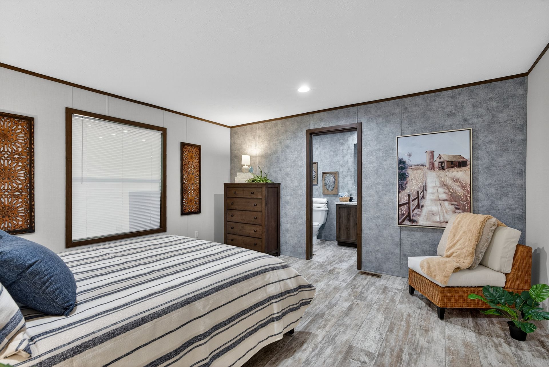 Bedroom with striped bed, dresser, mirror, chair, and gray walls in a modern interior.