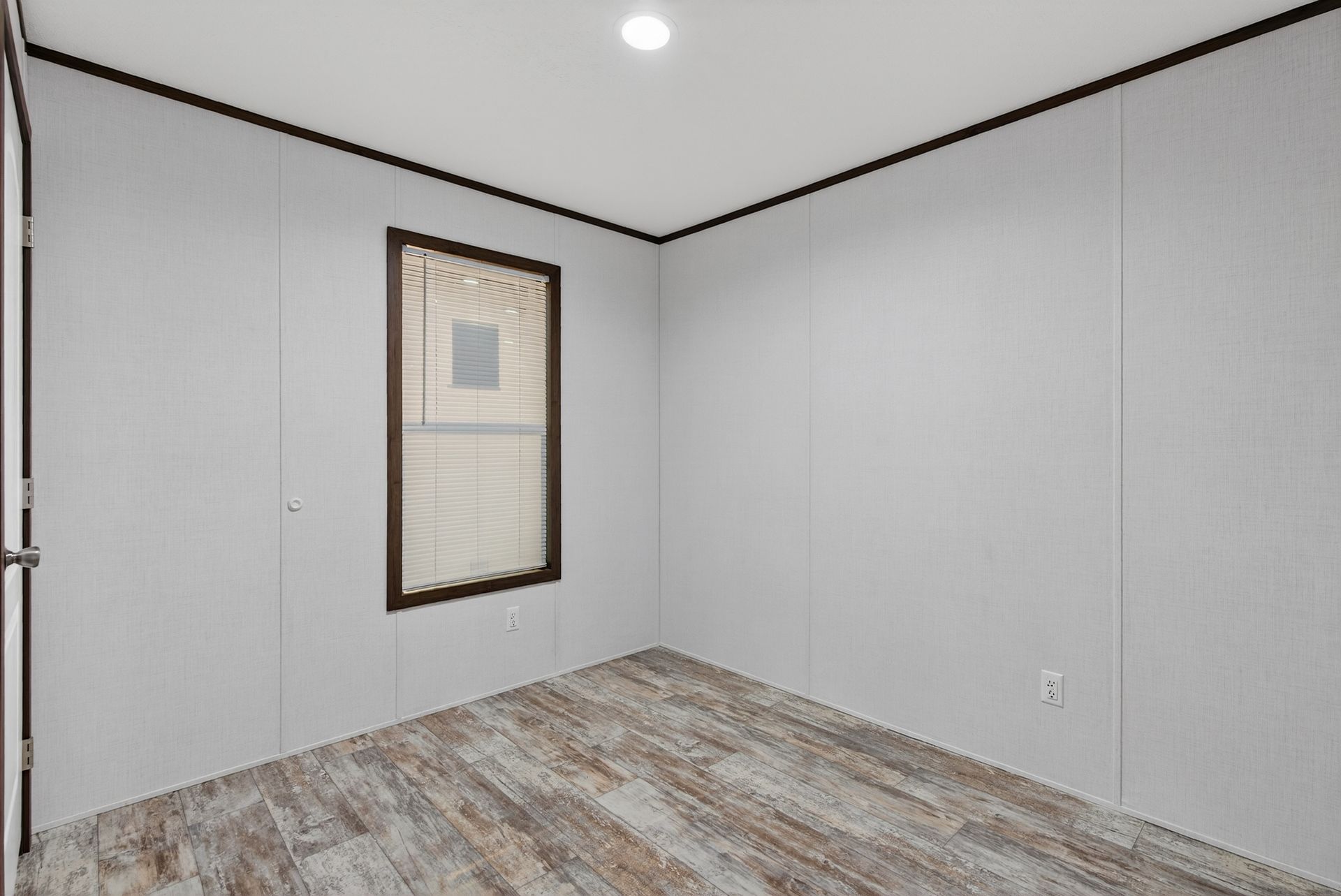 Empty room with gray walls, wood-look floor, recessed light, and a small window.