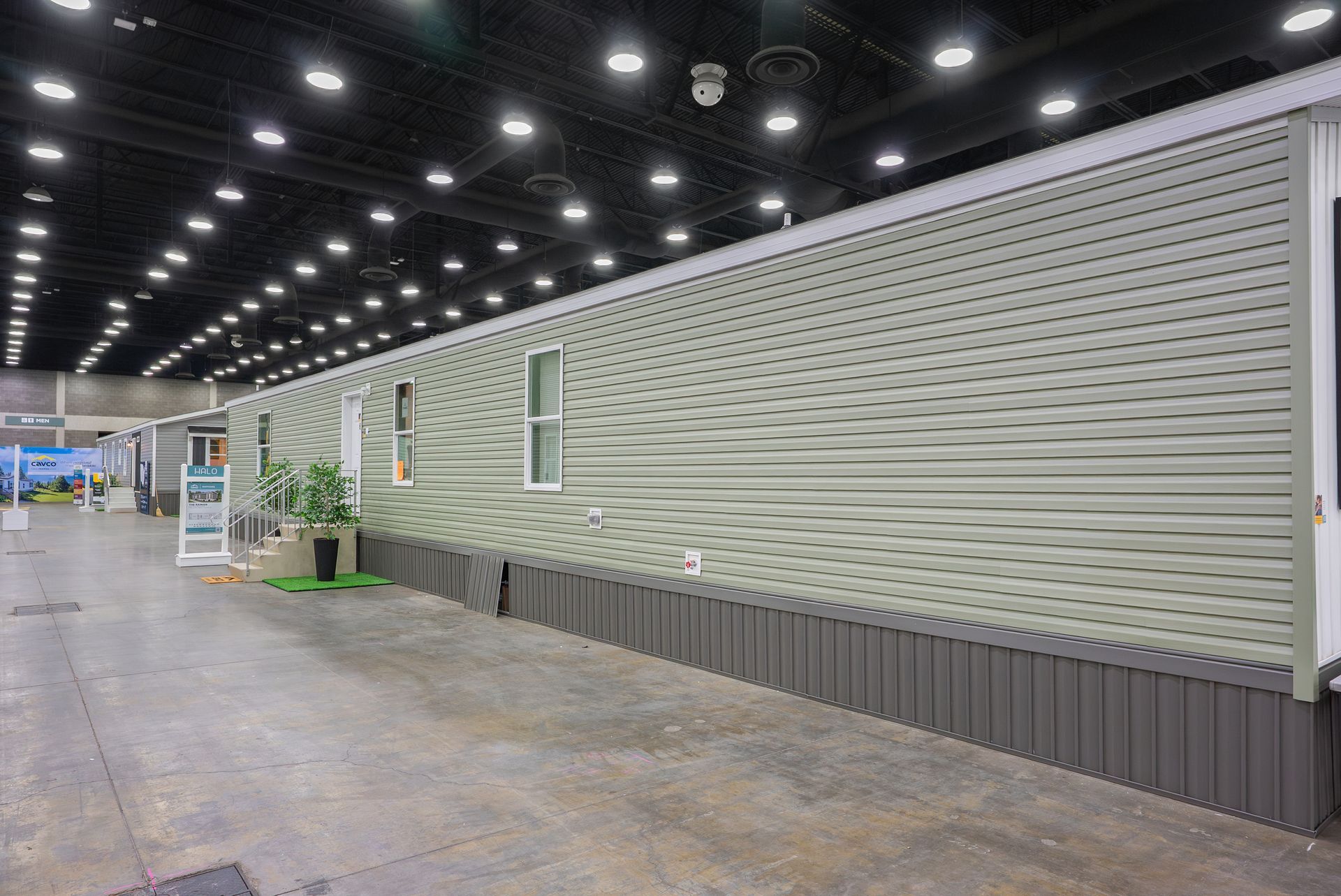 Empty exhibition hall with a long textured gray display wall and overhead spotlights