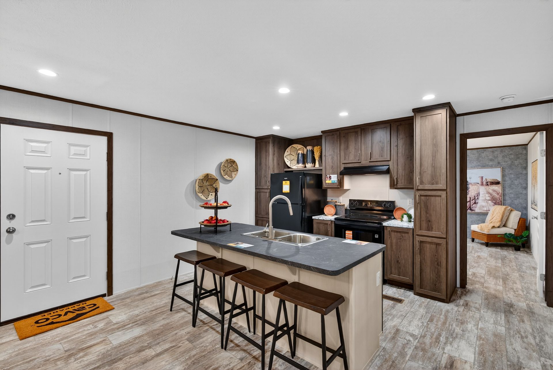 Open-concept kitchen and dining area with island, dark cabinets, and a white front door.