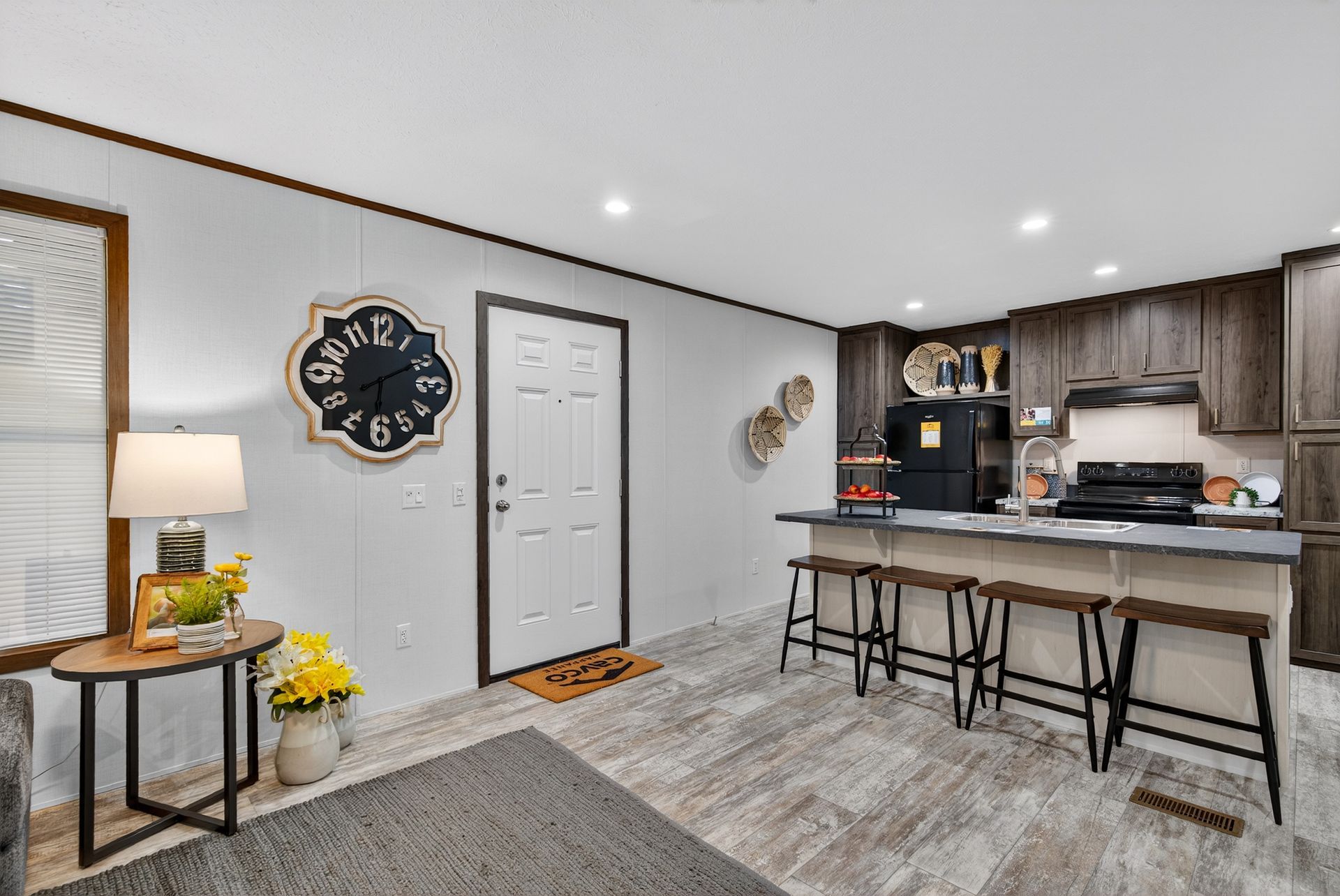 Modern open-plan kitchen and entryway with gray cabinets, island seating, and neutral decor