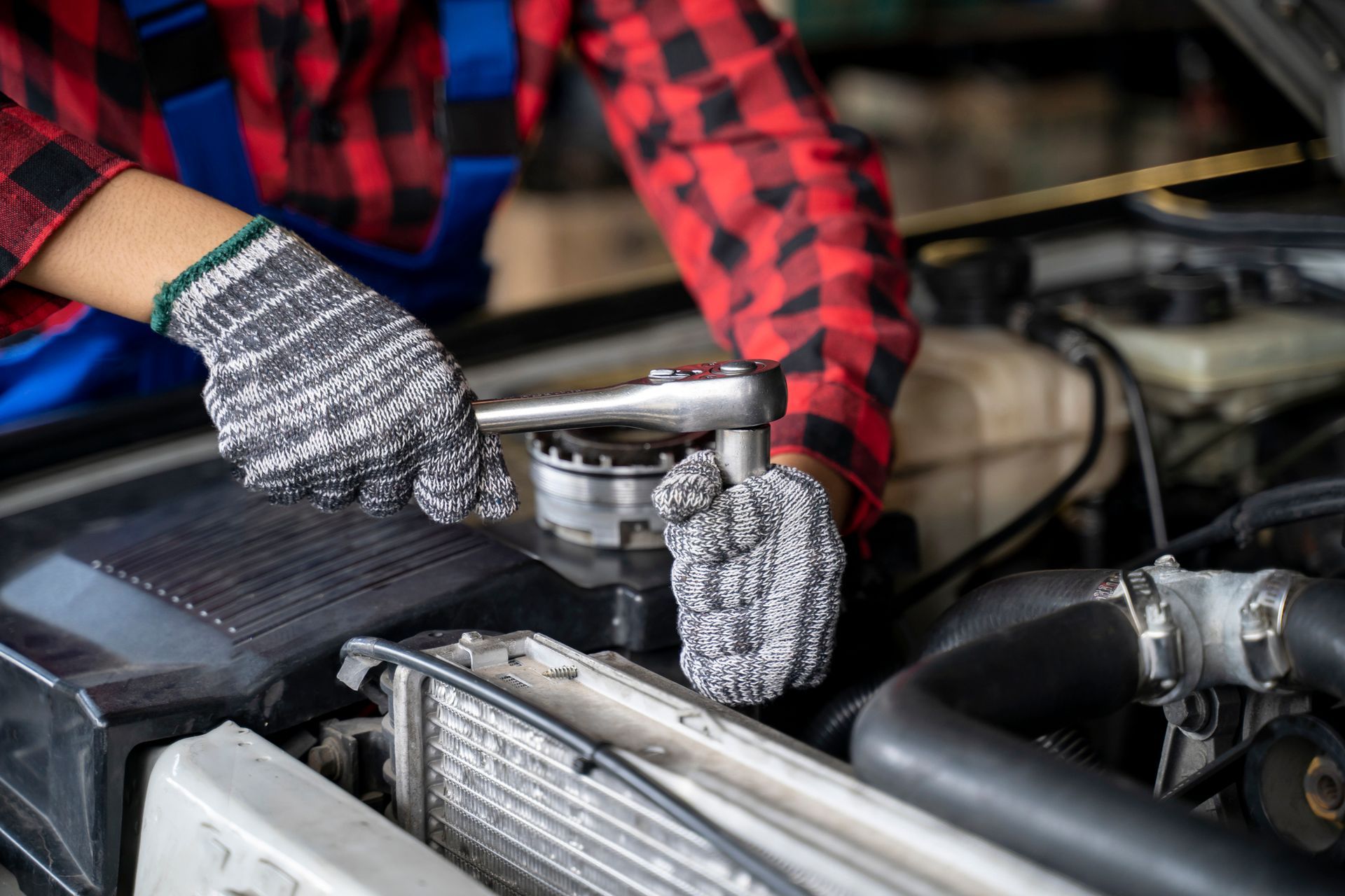 A mechanic wearing gloves repairing a car engine, focusing on transmission replacement service. A mechanic wearing gloves repairing a car engine, focusing on transmission replacement service.