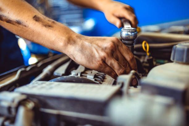 A mechanic repairing a car engine, focusing on transmission replacement service.