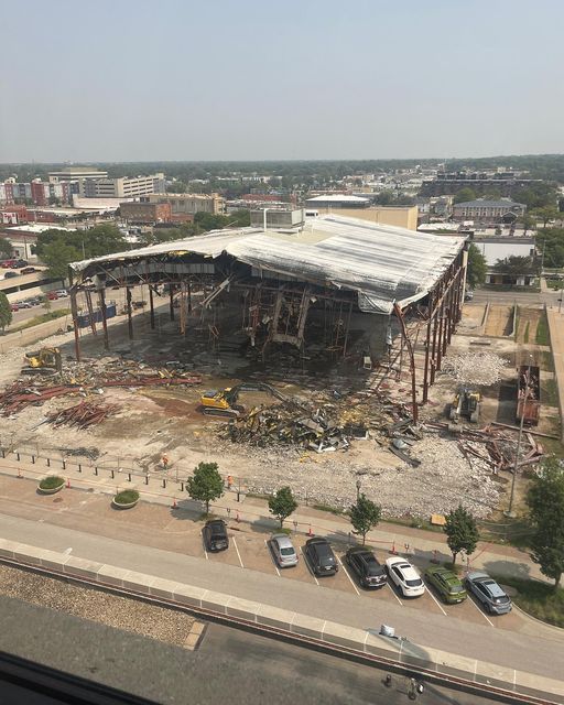 Partially demolished building with exposed steel frame, surrounded by debris, in an urban setting.