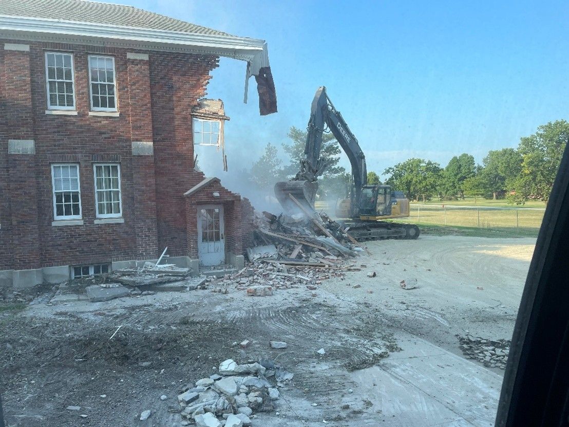 Bulldozer collecting remains of house making place.