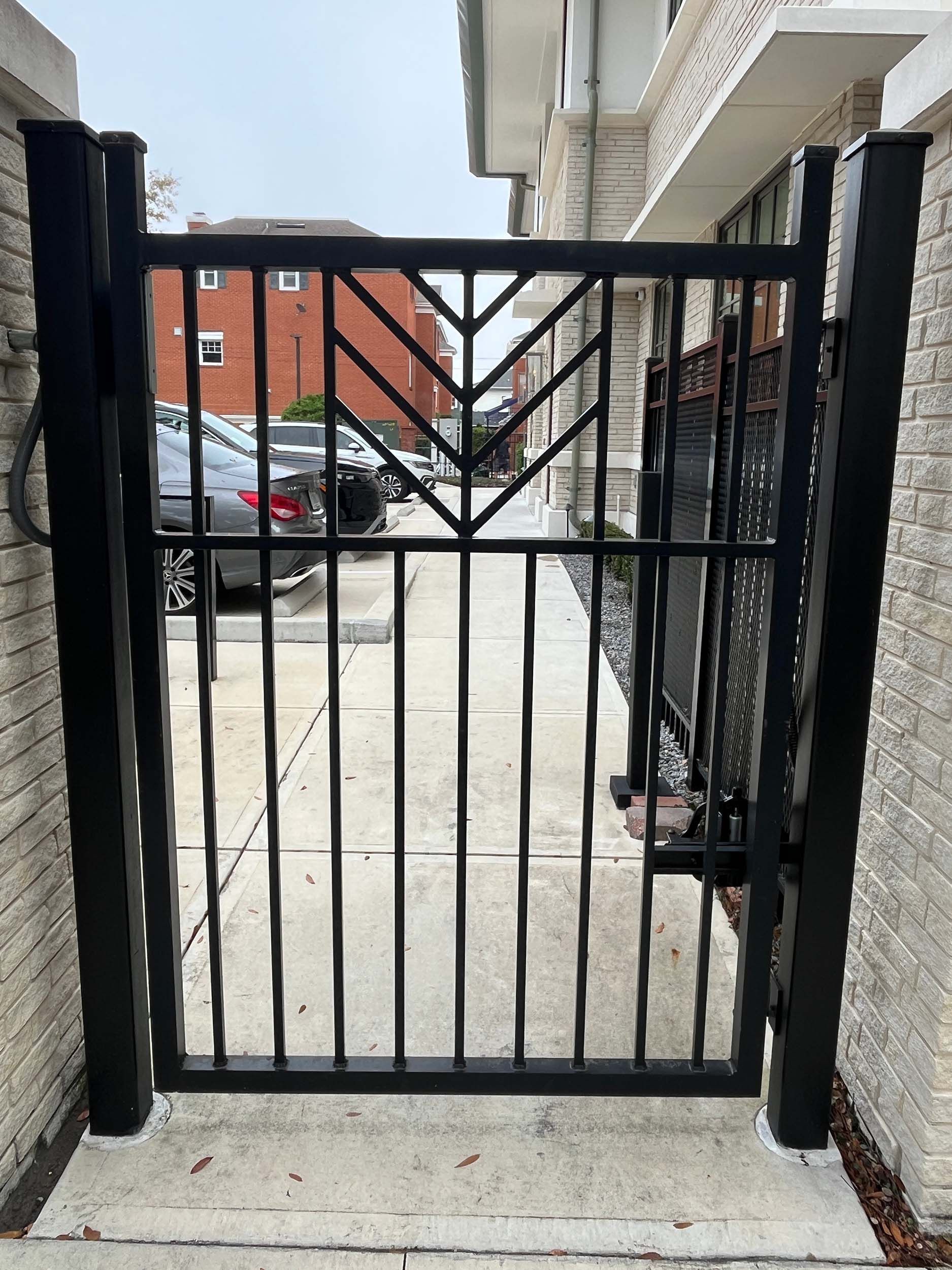 Stylish metal gate with brick columns by the sidewalk.
