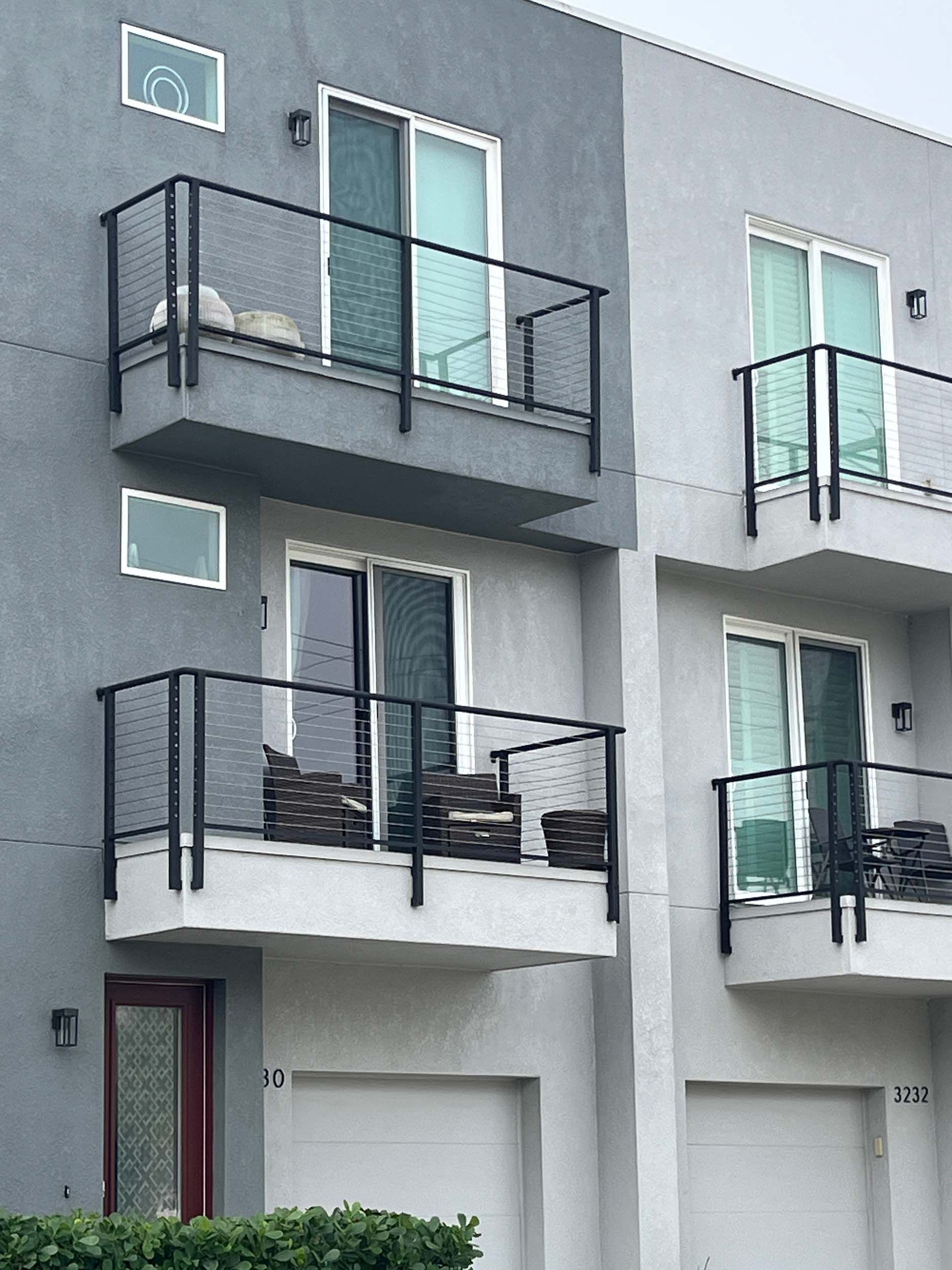 Modern gray townhomes with balconies and black railings.