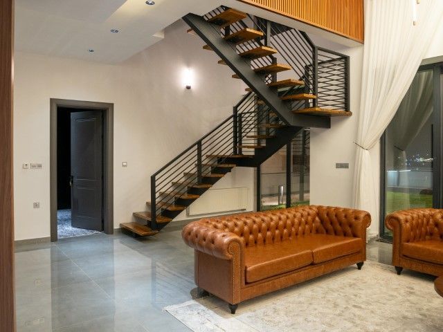 Modern interior with a brown leather sofa and a floating wooden staircase.
