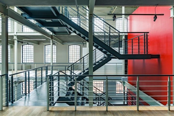 Multi-level interior with metal staircase and red accent wall.