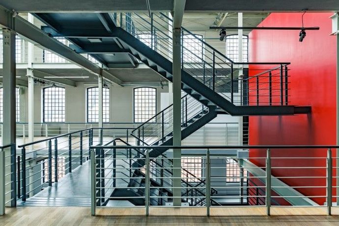 Multi-level interior with metal staircase and red accent wall.