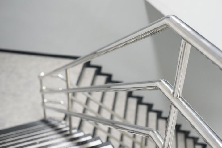 Stainless steel handrail and stairs viewed from above.