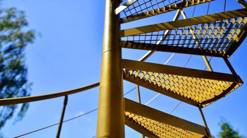 Yellow spiral staircase against a bright blue sky.