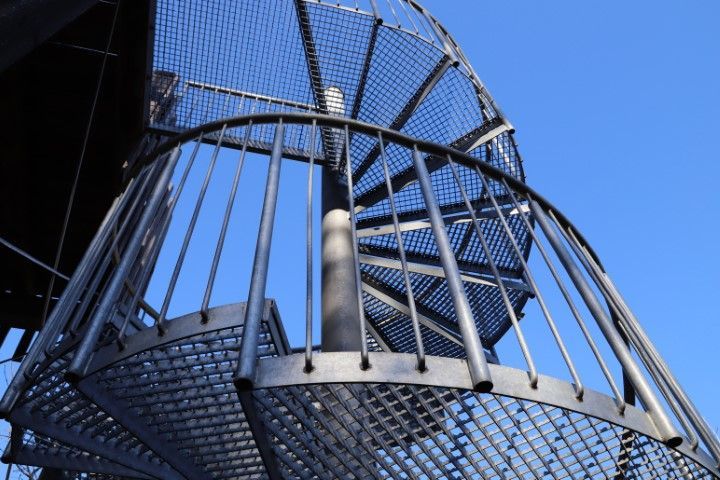 Spiral metal staircase against a clear blue sky.