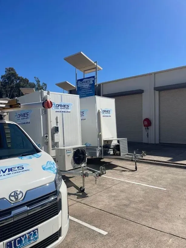 A White Van is Parked in a Parking Lot Next to a Trailer — Davies Refrigeration & Air Conditioning in Warana, QLD