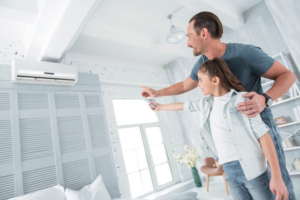 A Man and a Girl Are Adjusting the Air Conditioner in a Living Room — Davies Refrigeration & Air Conditioning in Warana, QLD