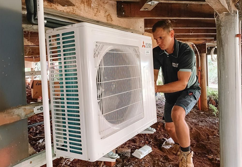 Man Installs an Air Conditioner Unit Under a House