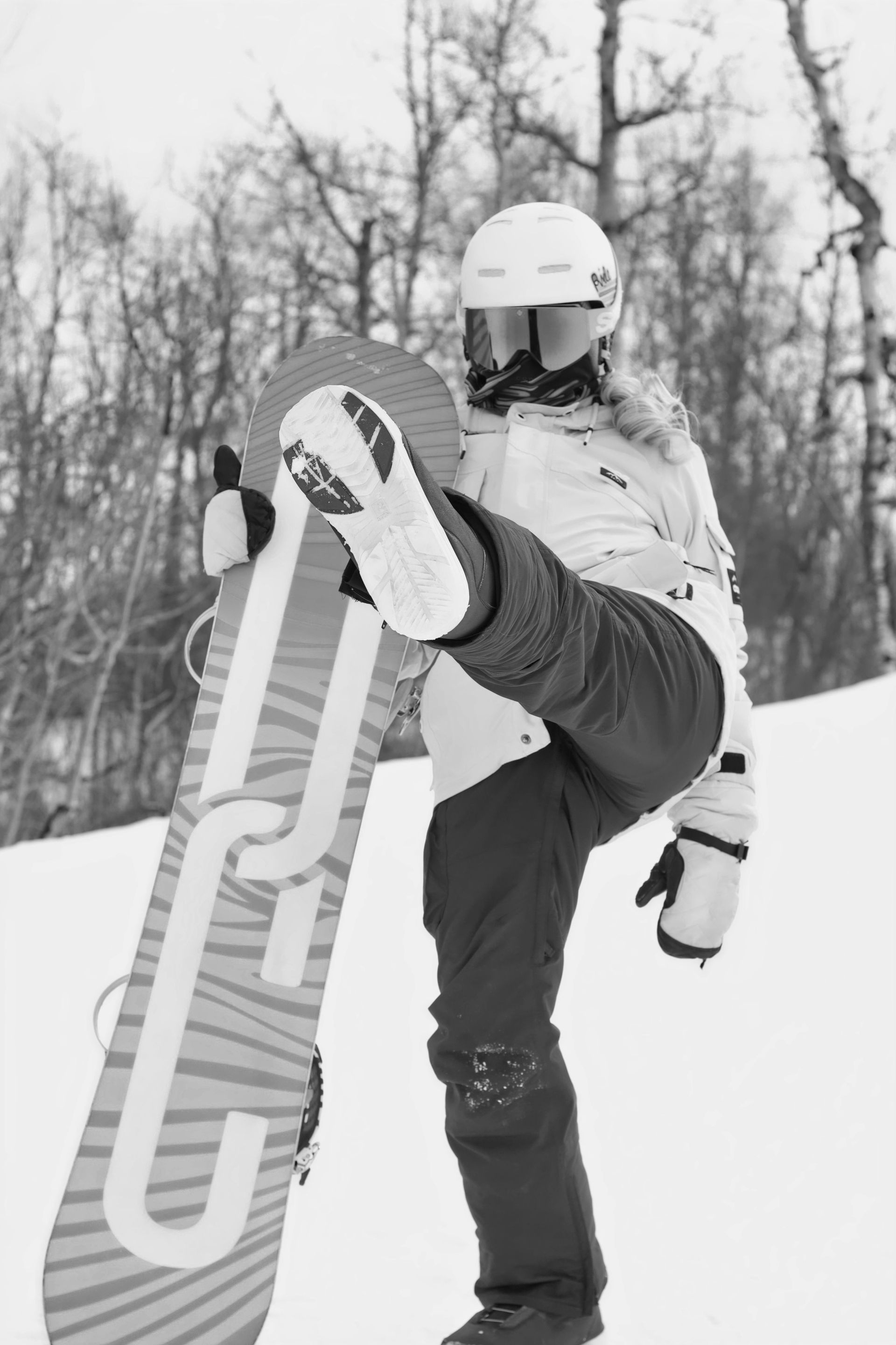 Two youth hockey players in team uniforms compete for the puck on an ice rink during a game.