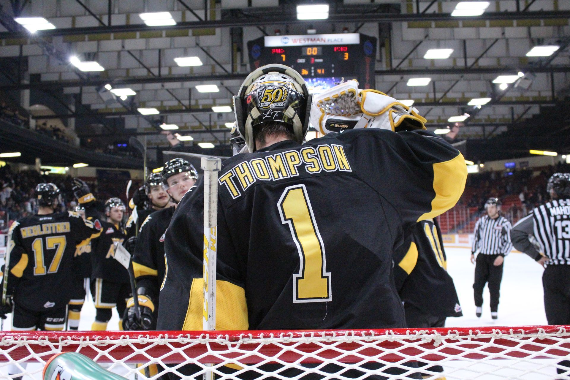 Hockey goalie wearing a black and gold jersey with 