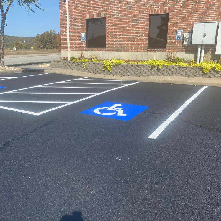 Exterior view of parking lot with freshly painted white lines and a blue handicap symbol on asphalt.