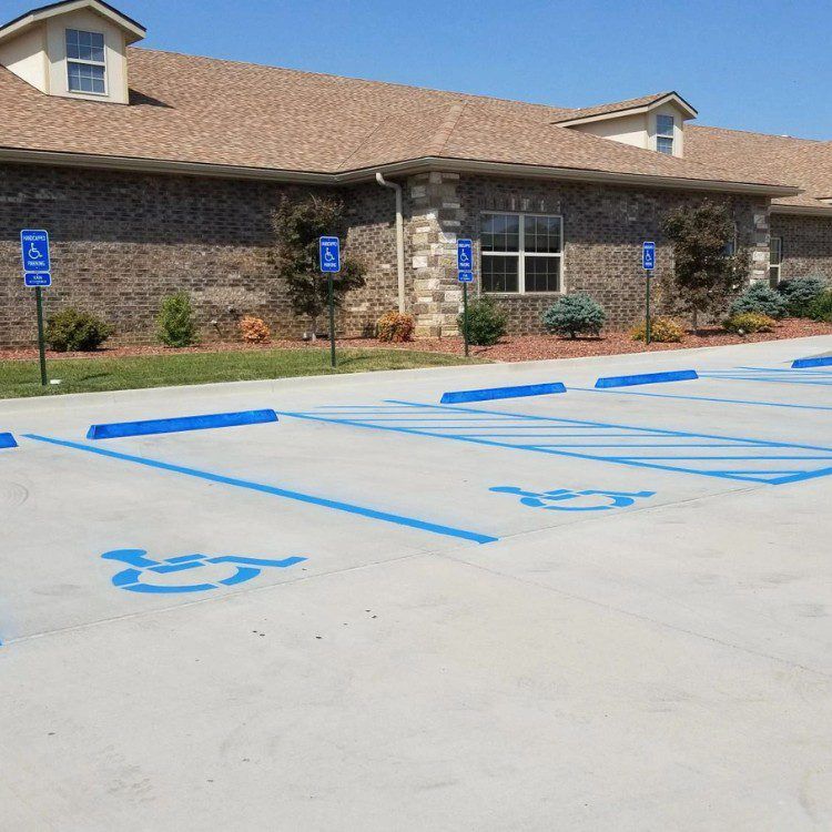 Handicap parking spaces painted blue outside a brick building under a clear sky.