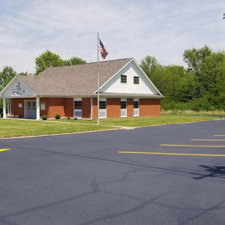 Brick building with American flag in front. Asphalt parking lot in foreground.