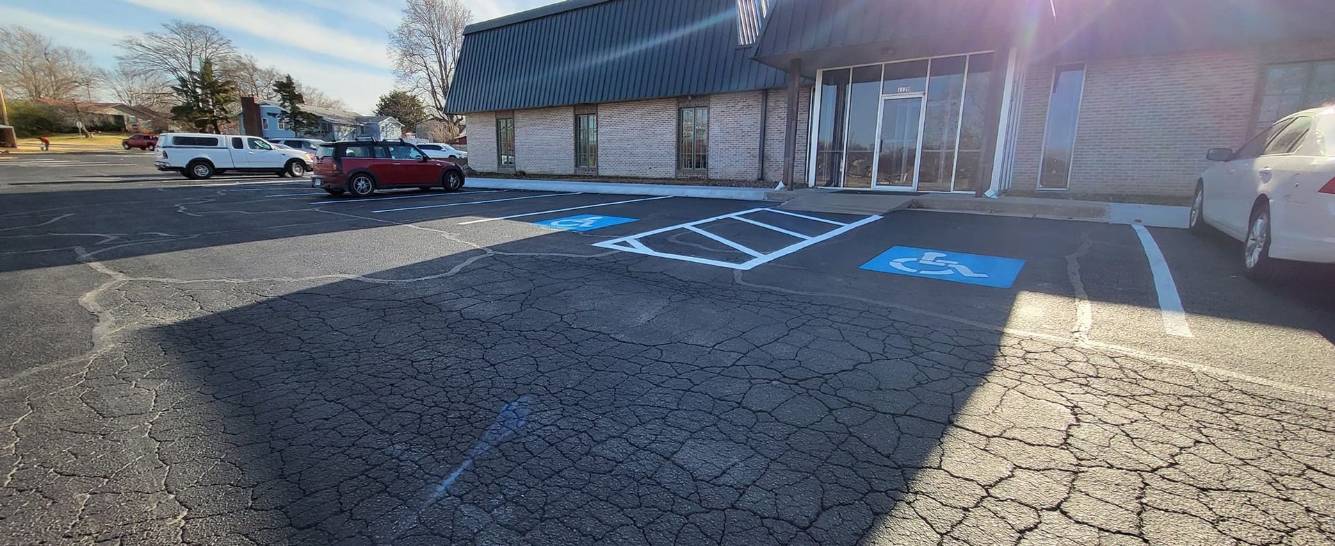 A parking lot with handicap parking spaces painted blue. A building is in the background.
