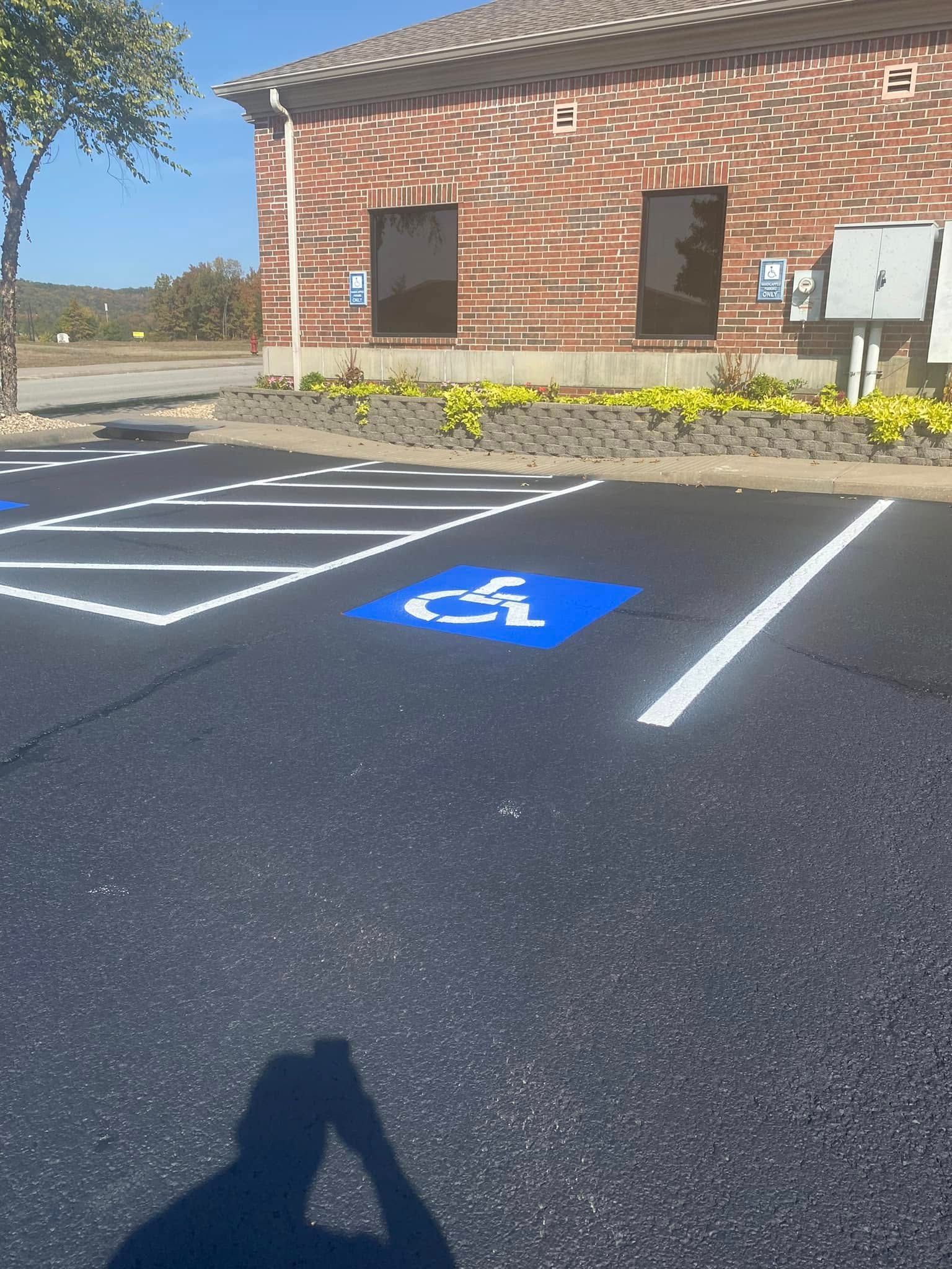 Handicap parking space with blue symbol on fresh asphalt. Brick building in background.