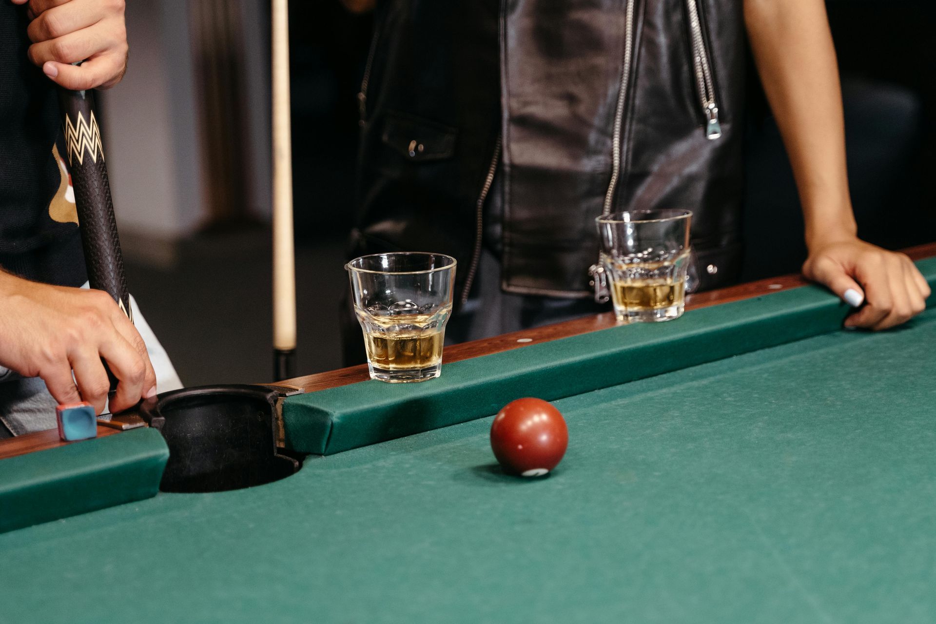 Two pool tables with red felt in a dimly lit bar, stained glass lamps overhead.