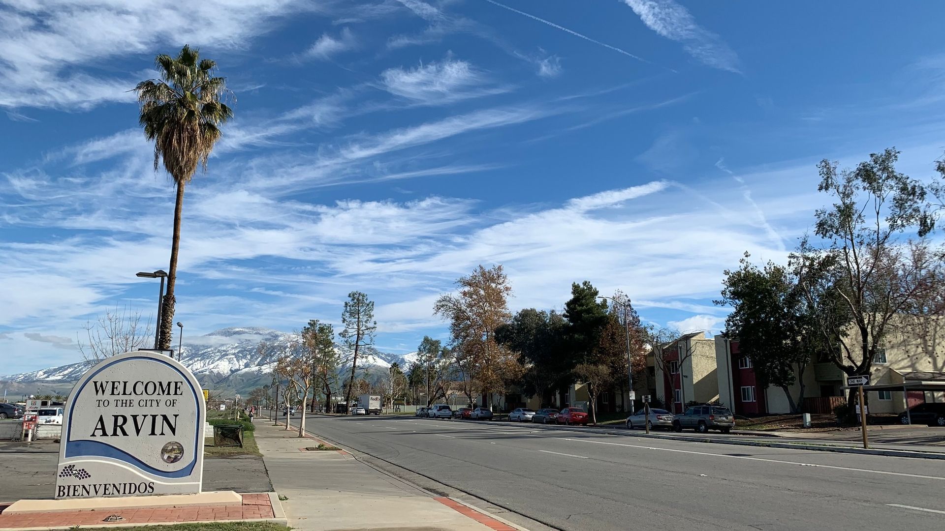 A street with a palm tree and a sign that says welcome to arvin