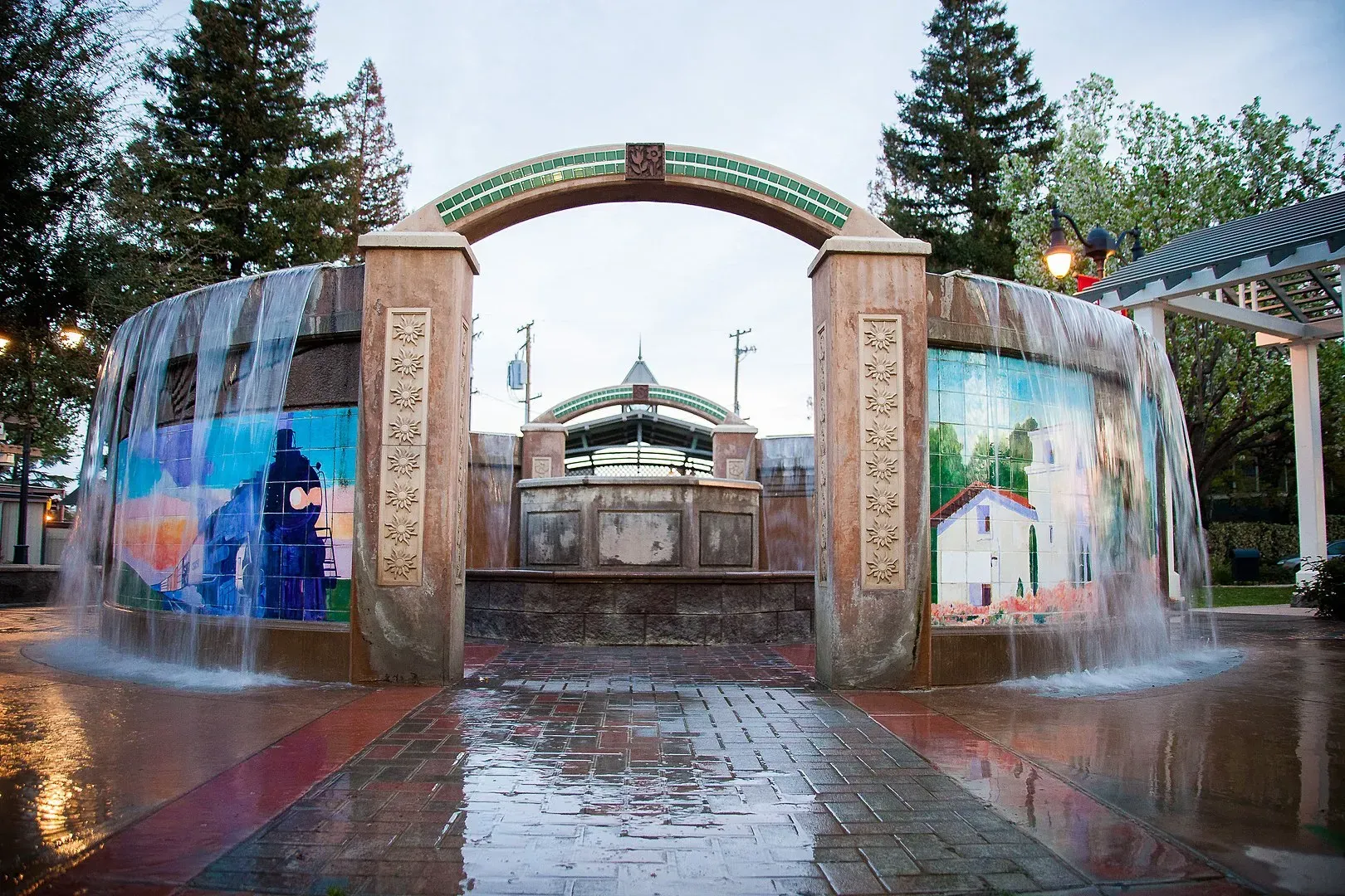 A fountain in a park with a mural on the side of it