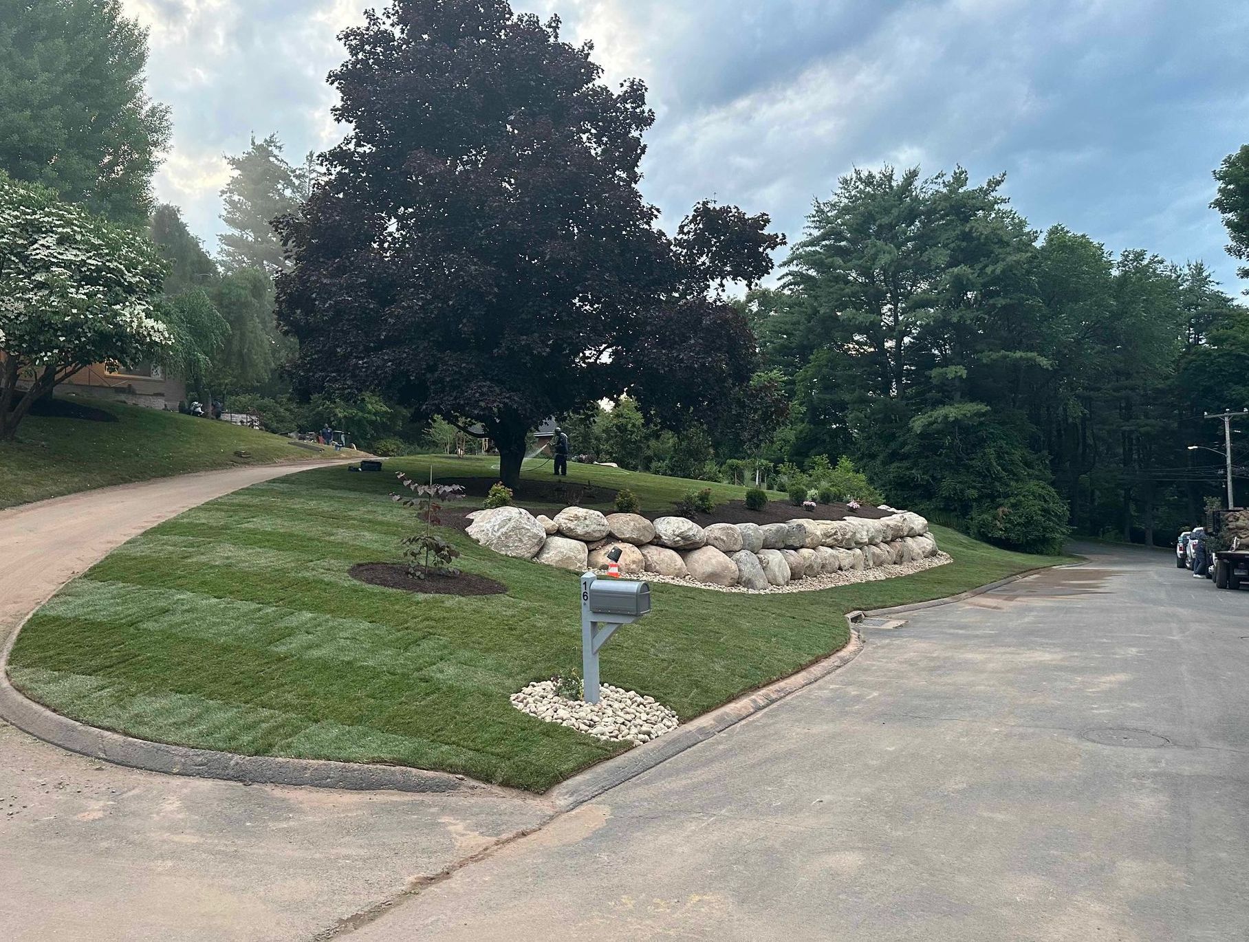Custom two tier natural boulder wall constructed in West Hartford with Sod Finish, River Rocks, and Planting Installs.