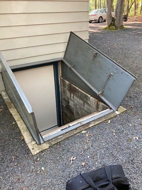 A basement door with the door open and a suitcase in front of it.