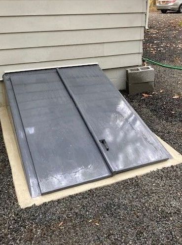 A gray door is sitting on the ground next to a house.