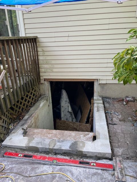 A basement window is being built into the side of a house.