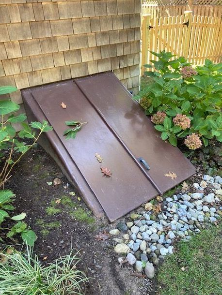 A brown door is sitting in the dirt in front of a house.