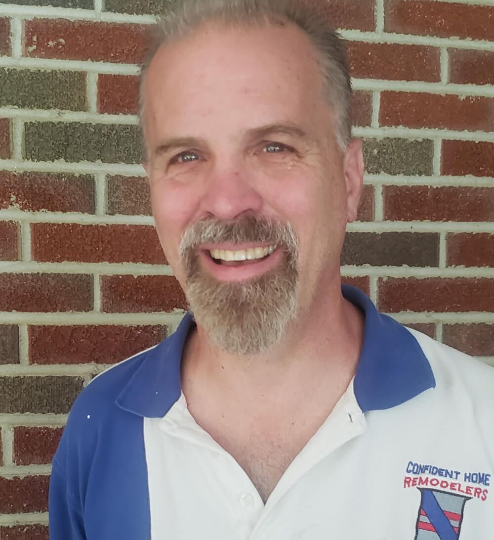 A man with a beard is wearing a shirt that says comfort home remodelers
