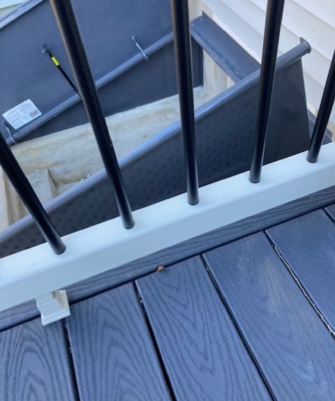 A close up of a railing on a deck with stairs in the background.