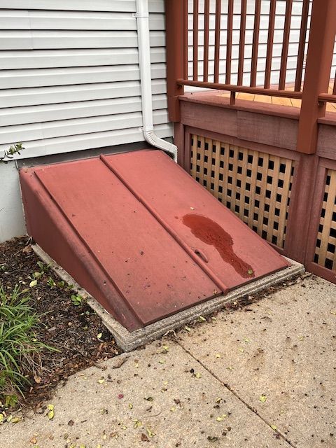 A red door is sitting on the sidewalk next to a house.