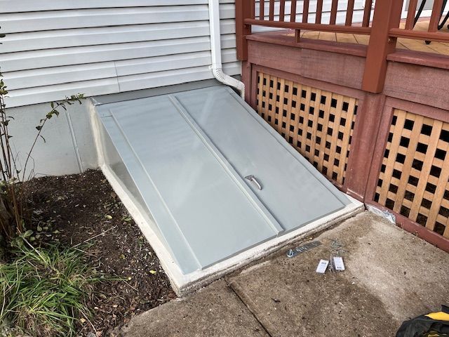 A gray door is sitting on the sidewalk next to a house.