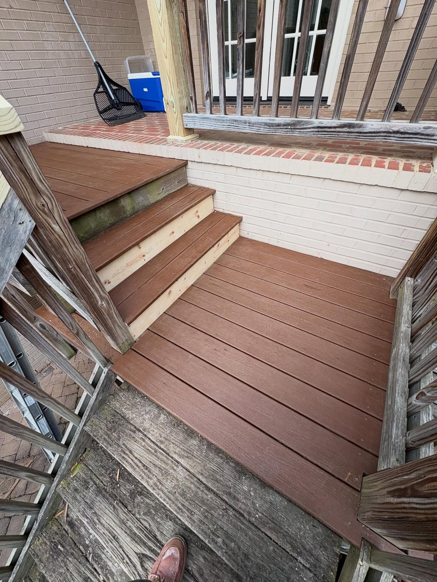 Wooden porch deck with brown steps, white railing, and a blue bucket in the corner