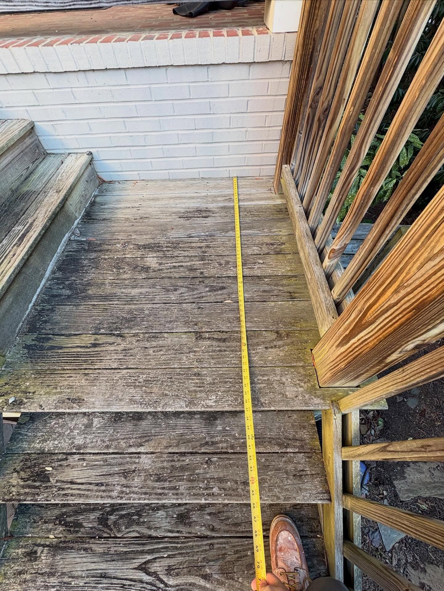 Yellow measuring tape stretched along worn wooden steps beside a porch railing.